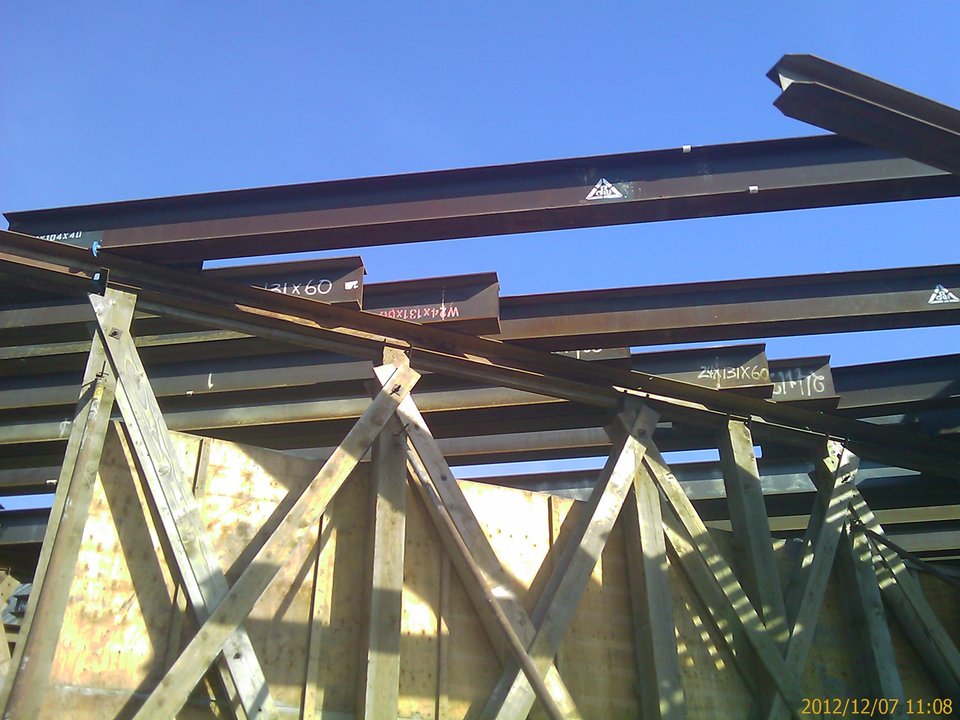 Site photo, 7 December 2012: steel stringers stenciled W24x131x60 bearing on a braced timber falsework bent